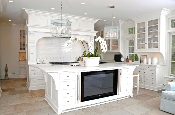 Bright white kitchen with a large island, black stovetop, and glass-front cabinets in a spacious home.