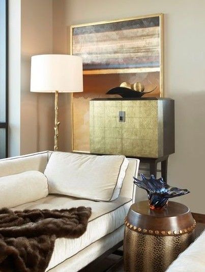 Modern living room with cream sofa, floor lamp, gold cabinet, and round bronze side table