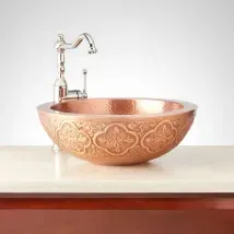 Copper embossed bathroom sink with a chrome faucet on a white countertop
