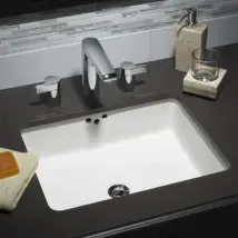 Modern bathroom sink with black countertop, chrome faucet, soap dispenser, and folded towel