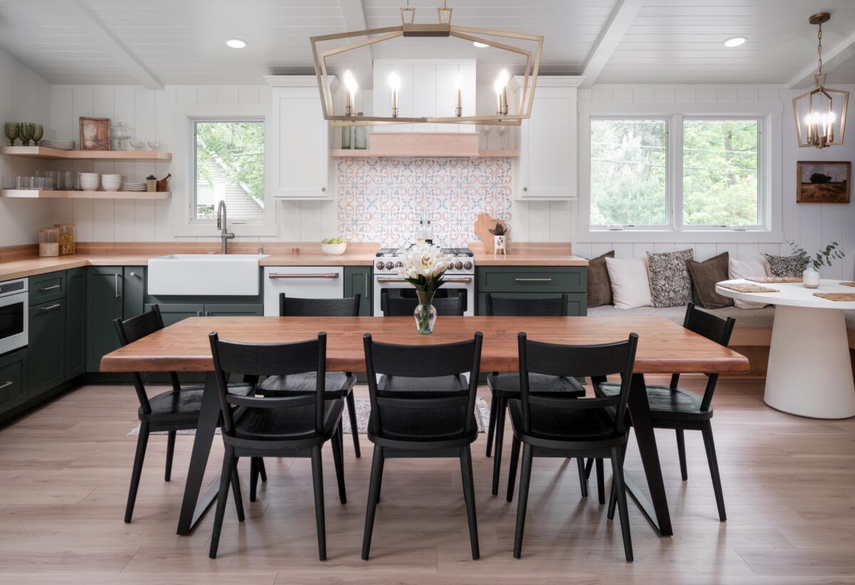 Modern kitchen and dining area with a wooden table, black chairs, white cabinets, and large windows