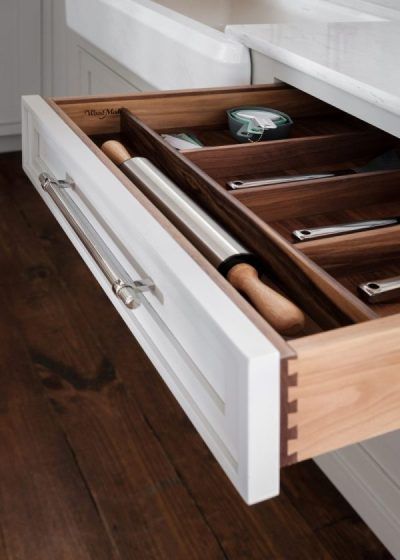 Open drawer with wooden kitchen utensils organizer in a white cabinet