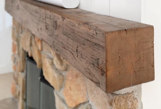Rustic wooden mantel over a stone fireplace
