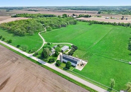 Aerial view of a rural landscape with green fields, a winding path, and a small building near a road.