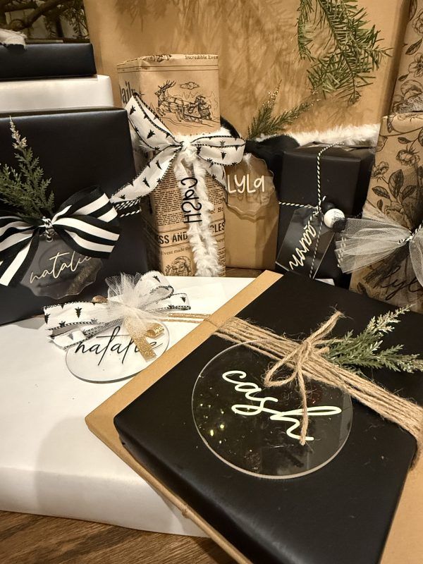 Black-and-white gift boxes tied with ribbon on a white couch and wooden tray