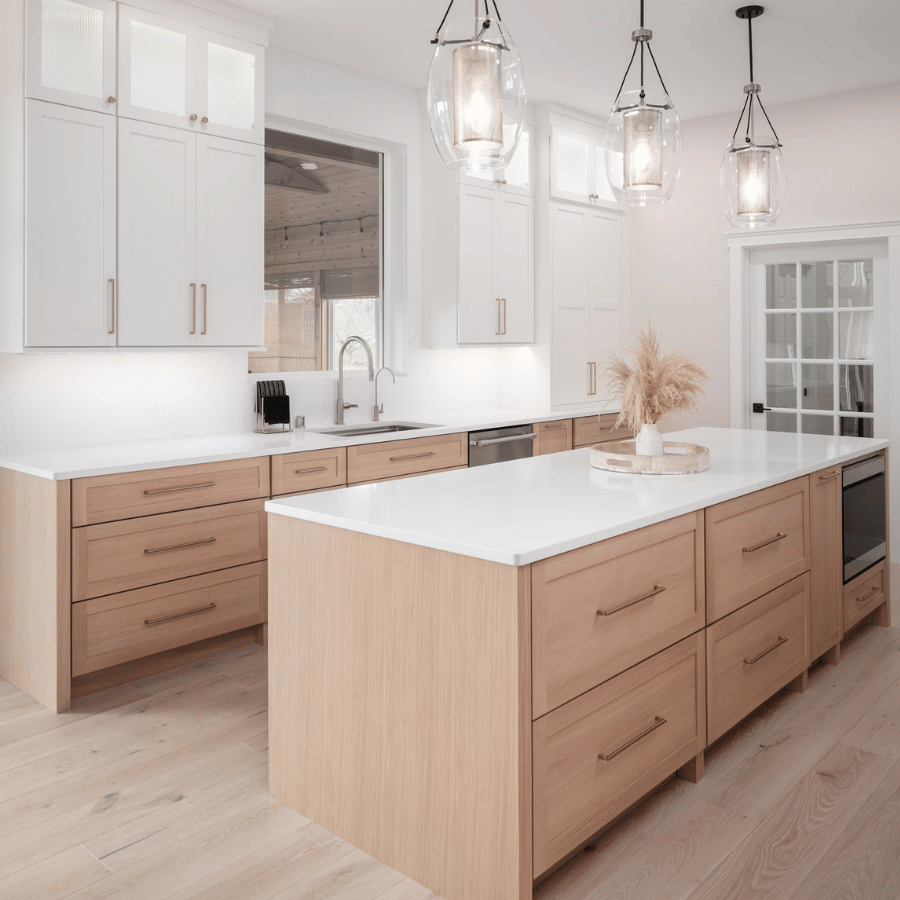 Bright modern kitchen with white cabinets, wood island, pendant lights, and light wood floors