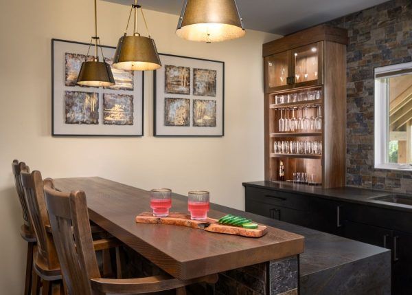 Modern dining room with wooden table, pendant lights, framed wall art, and built-in wine storage