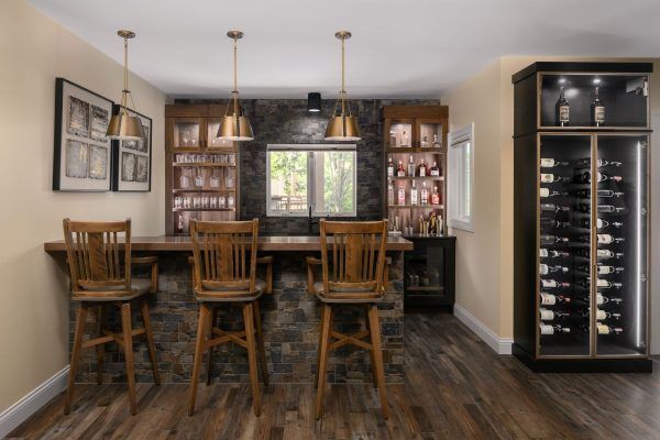 Dining room with wooden bar stools, wine cabinet, and large window in a warm, rustic interior