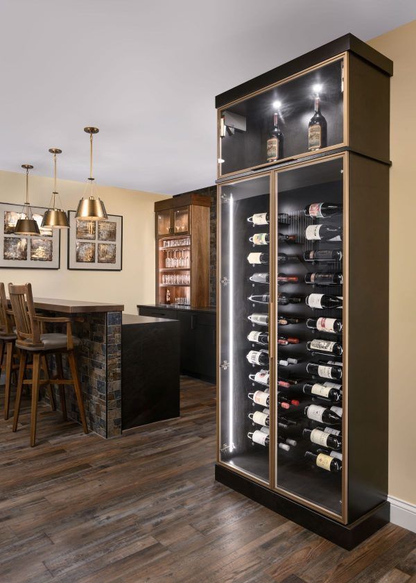 Modern home wine display cabinet in a dining room with bar seating and pendant lights