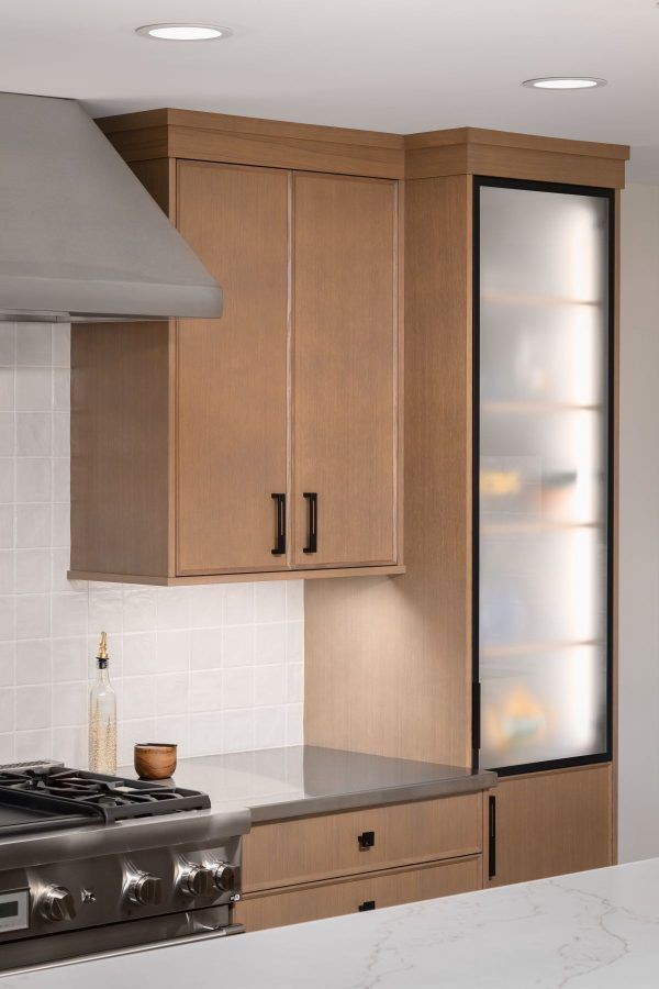 Modern kitchen with wood cabinets, stainless range, and frosted glass pantry door