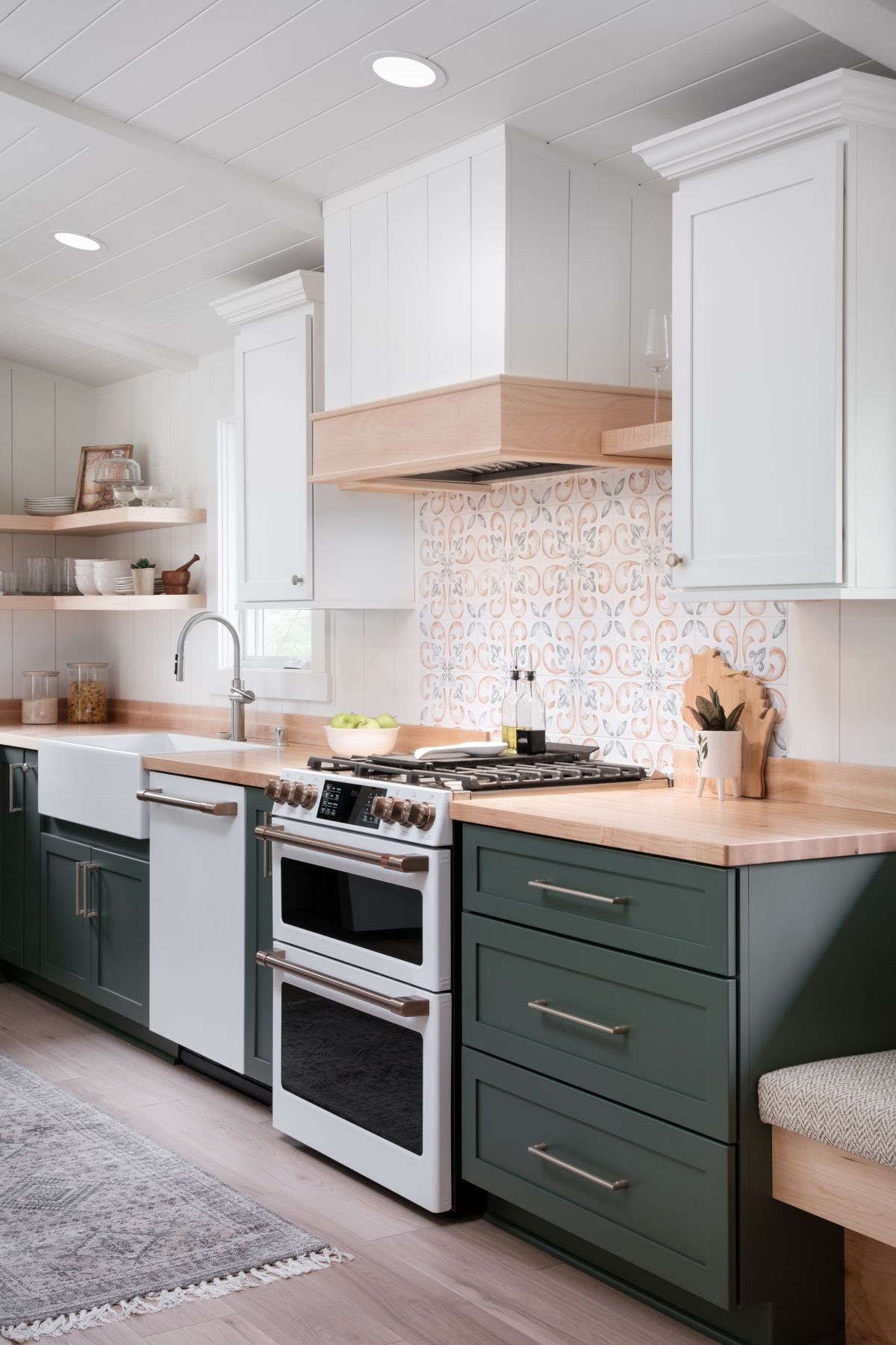 Modern kitchen with white cabinets, green lower drawers, wood countertops, and a stainless-steel stove.