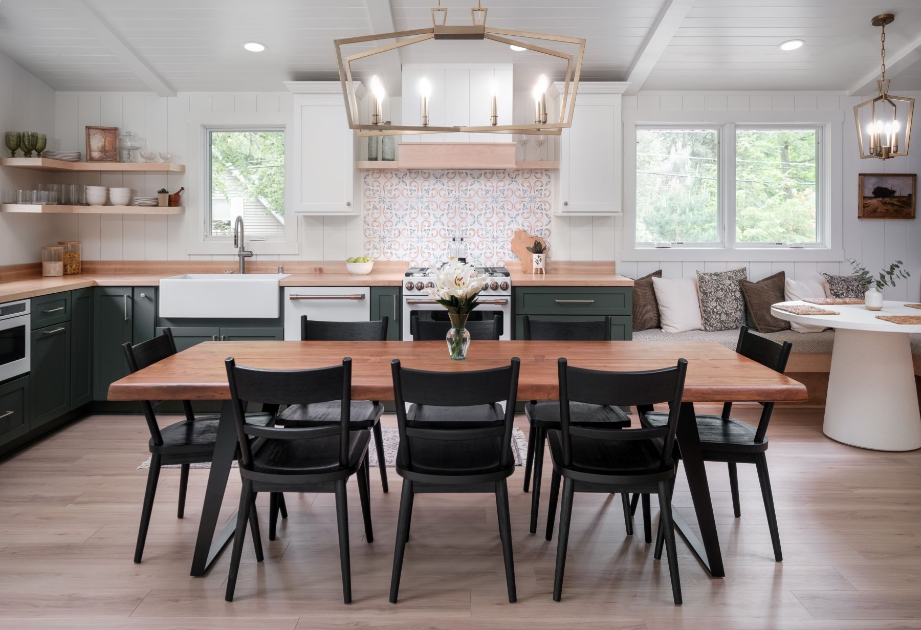 Modern kitchen and dining area with black chairs, white cabinets, and light wood floors