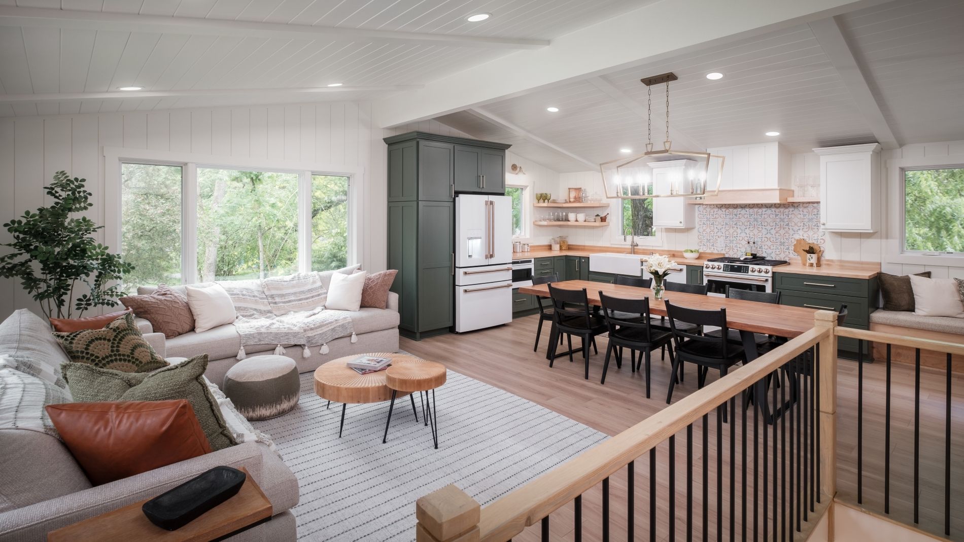 Bright open living room and kitchen with white sofas, dining table, and large windows