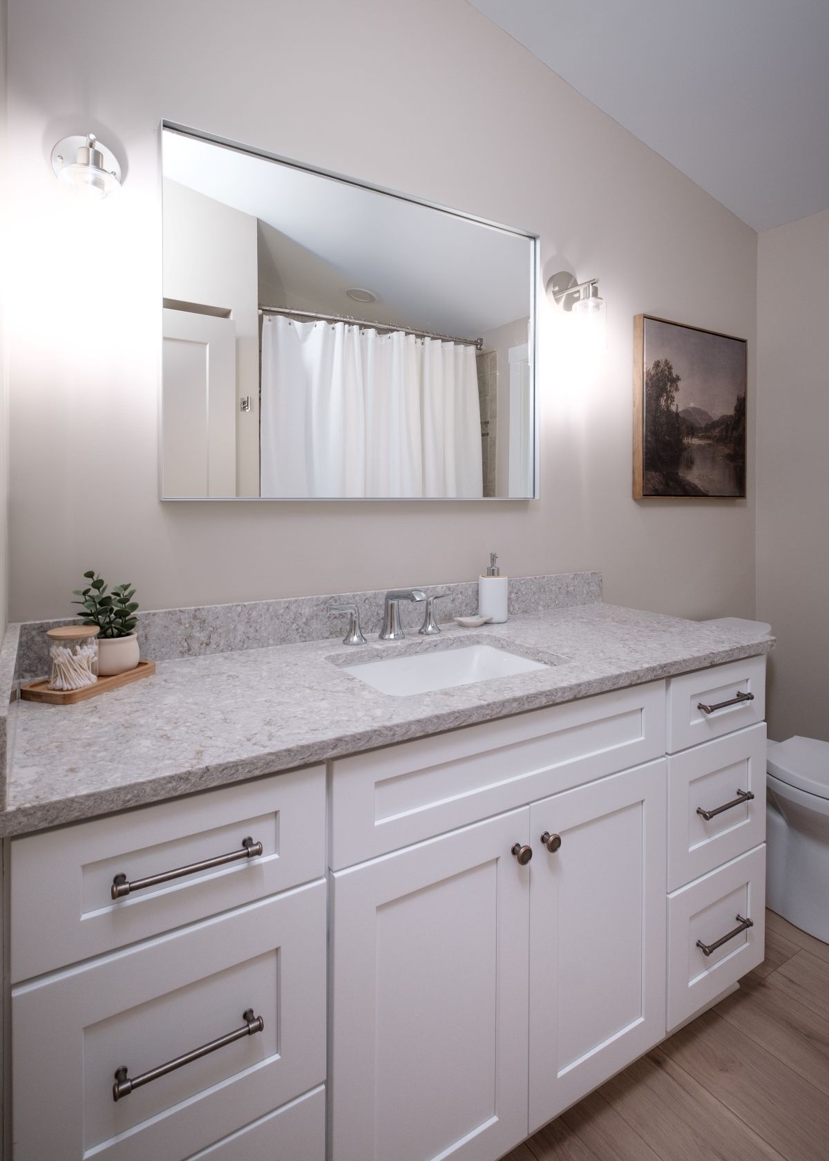 Bright modern bathroom vanity with marble countertop, double sink, large mirror, and white cabinets