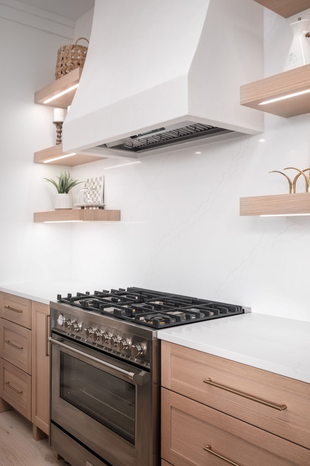 Modern kitchen with stainless steel stove, white range hood, and light wood cabinets