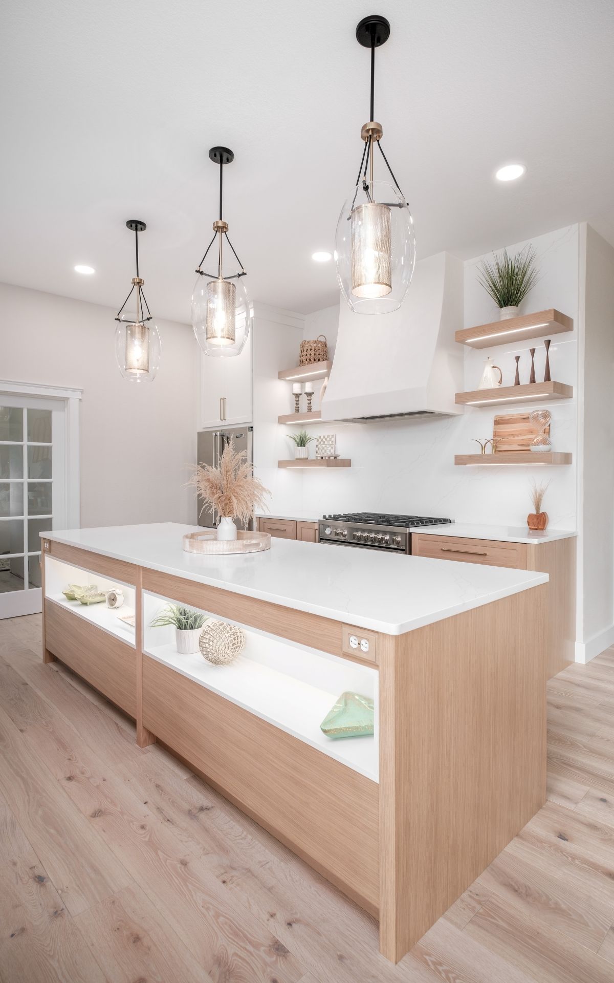 Bright modern kitchen with white cabinets, wood island, pendant lights, and open shelves