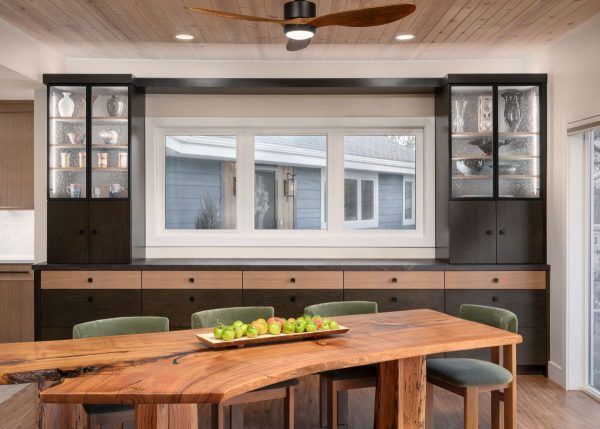 Modern dining room with wood table, built-in cabinets, large window, and ceiling fan
