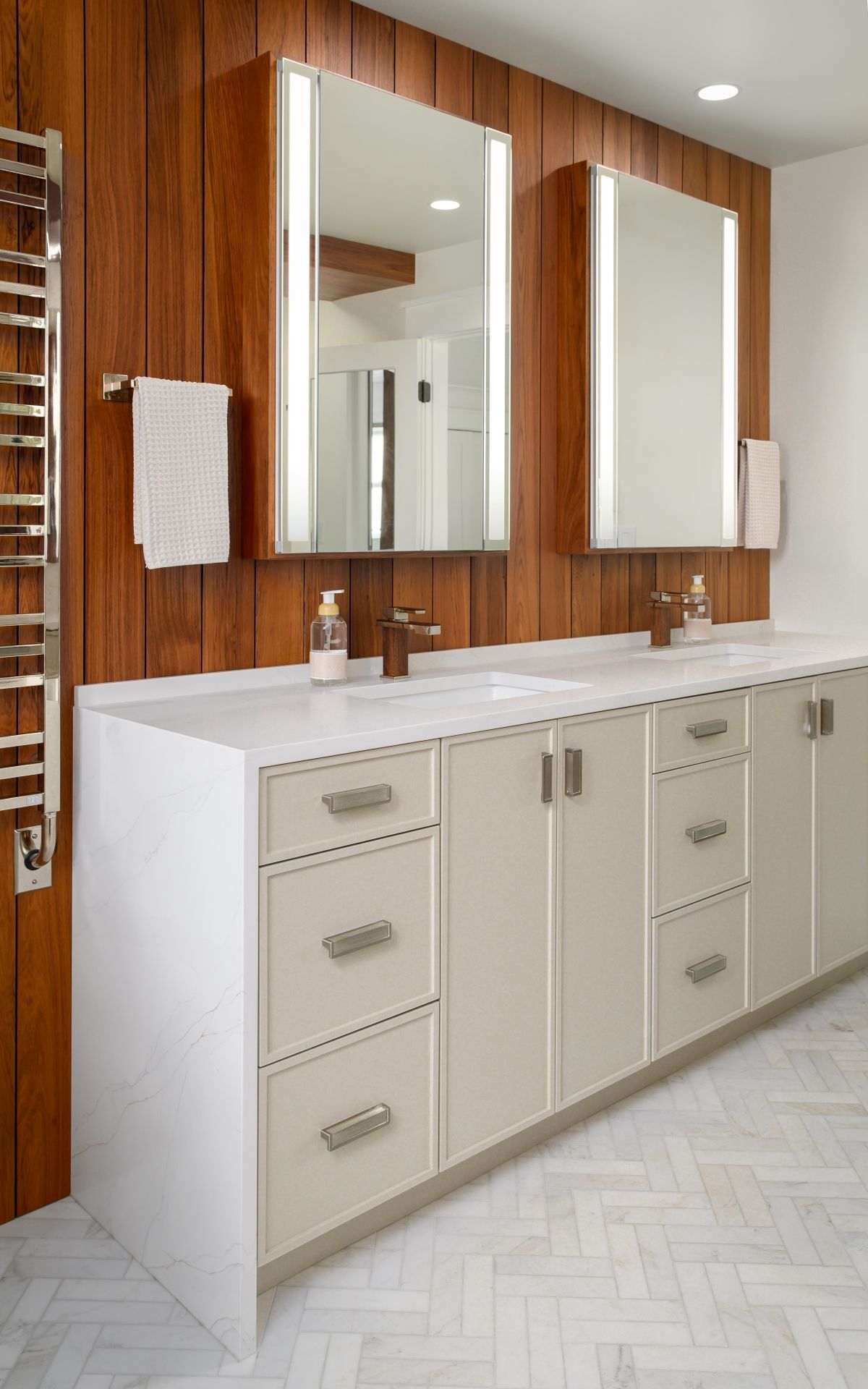Modern bathroom vanity with double sinks, white cabinets, and wood-paneled wall with mirrors