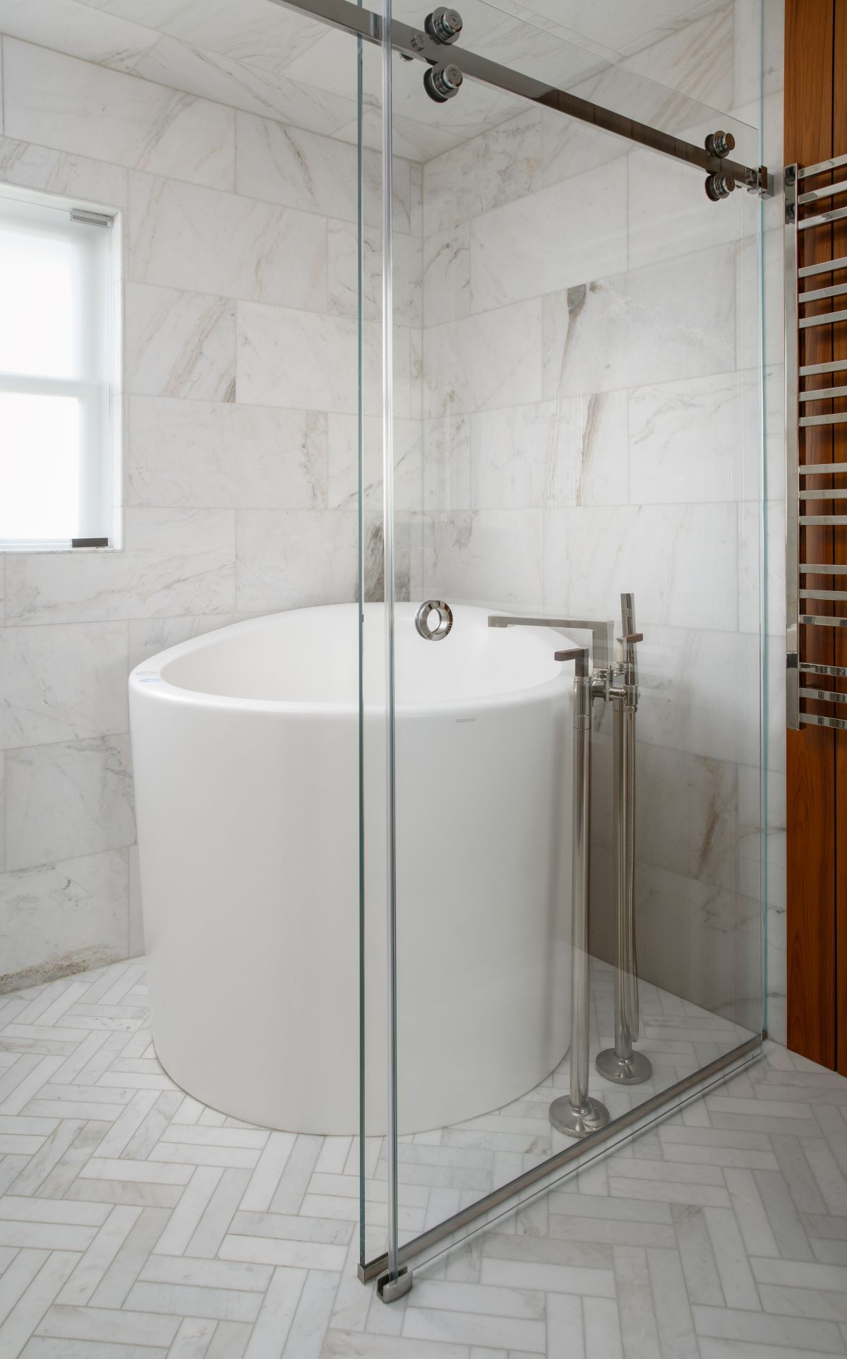 Modern bathroom with a freestanding tub and glass-enclosed shower on marble tile floor