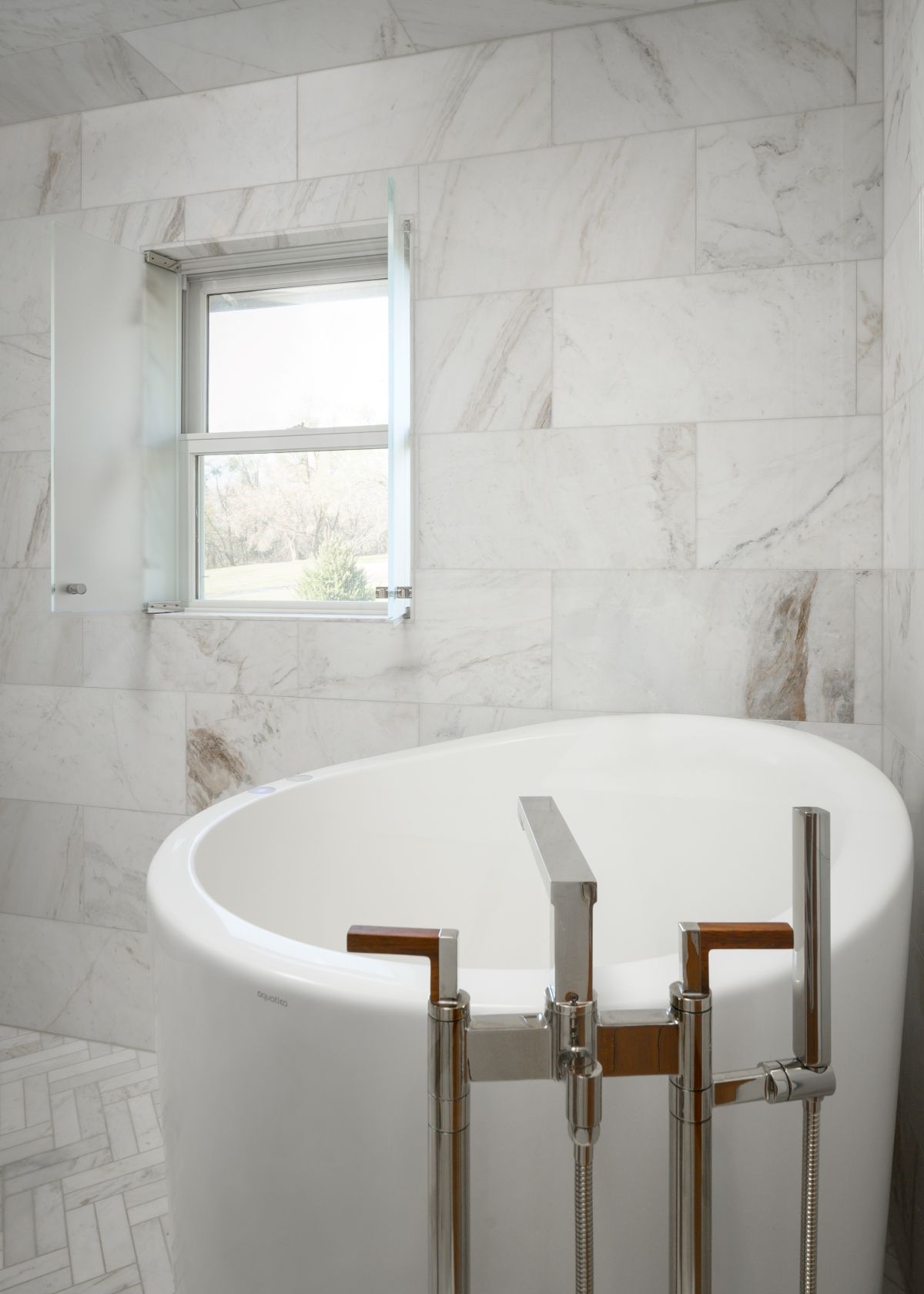 White marble bathroom with a round soaking tub and small window