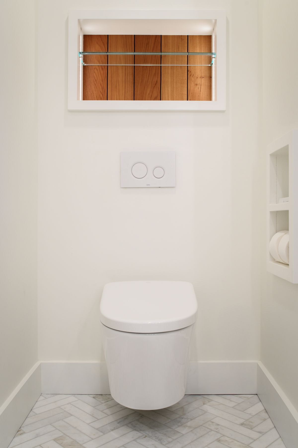 Small white bathroom with a toilet, flush button, narrow window, and gray hex tile floor.