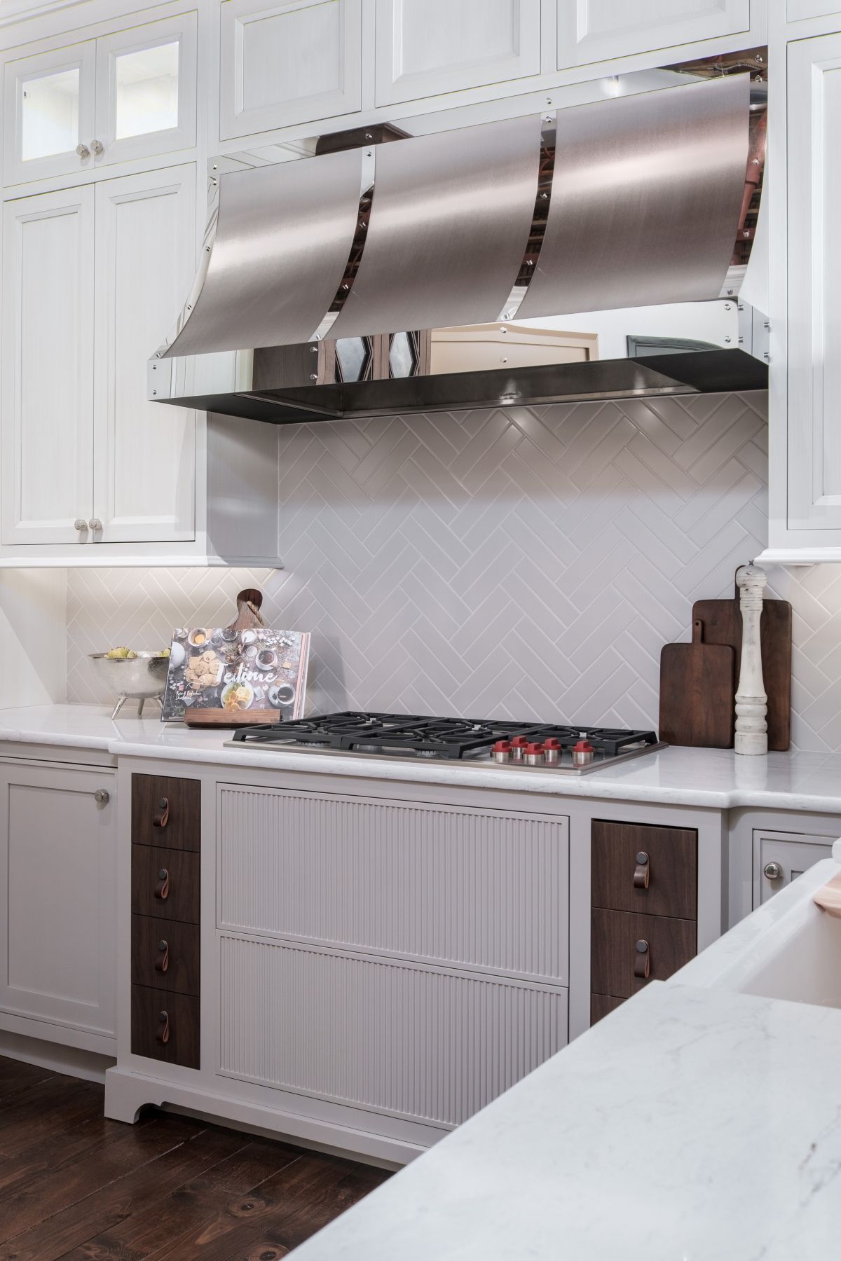 Modern kitchen with white cabinets, a stainless-steel range hood, and a marble island countertop