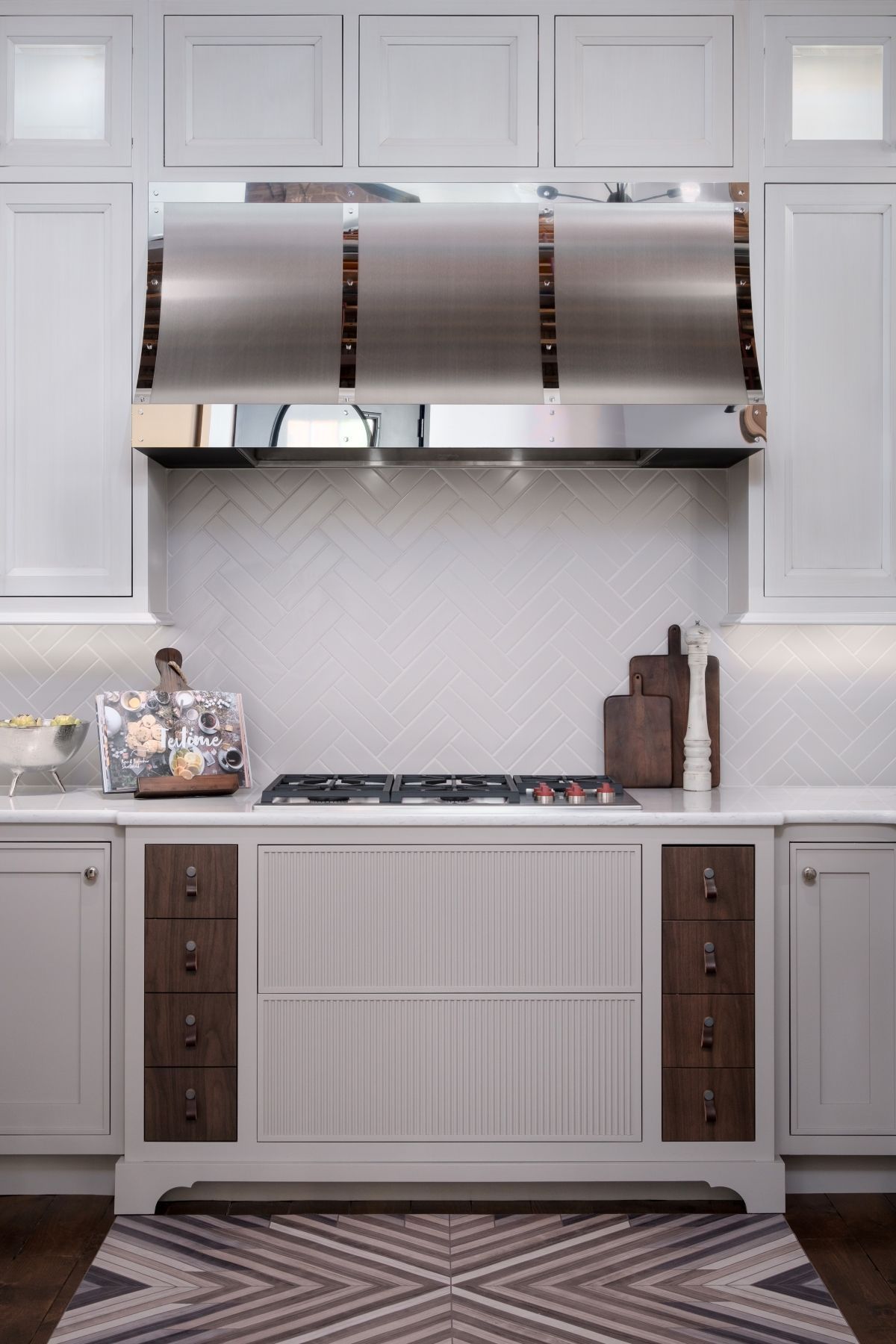 Modern kitchen with stainless steel range hood, white cabinetry, and dark wood accents
