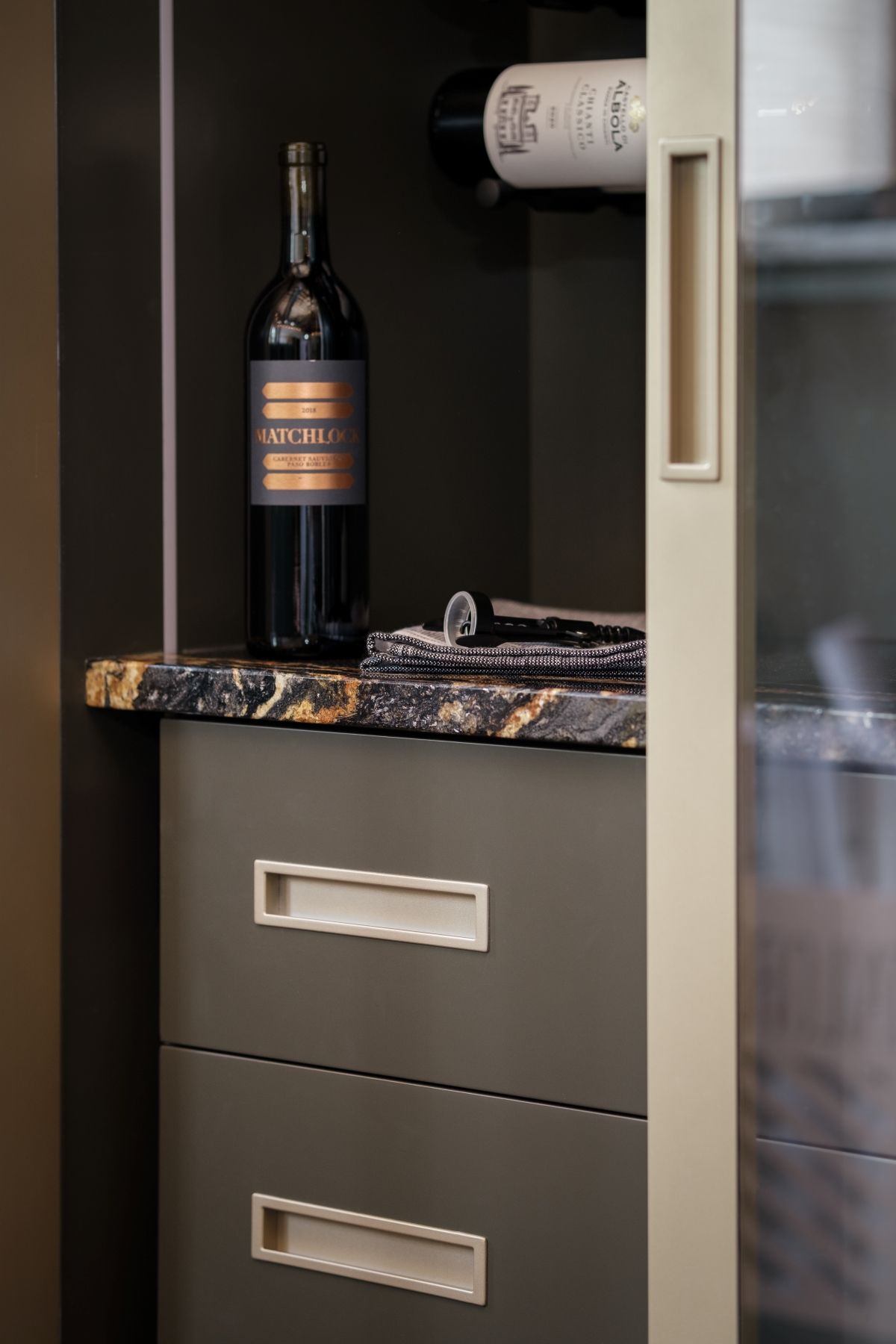 Wine bottle on a marble-topped cabinet beside a sliding door in a modern interior