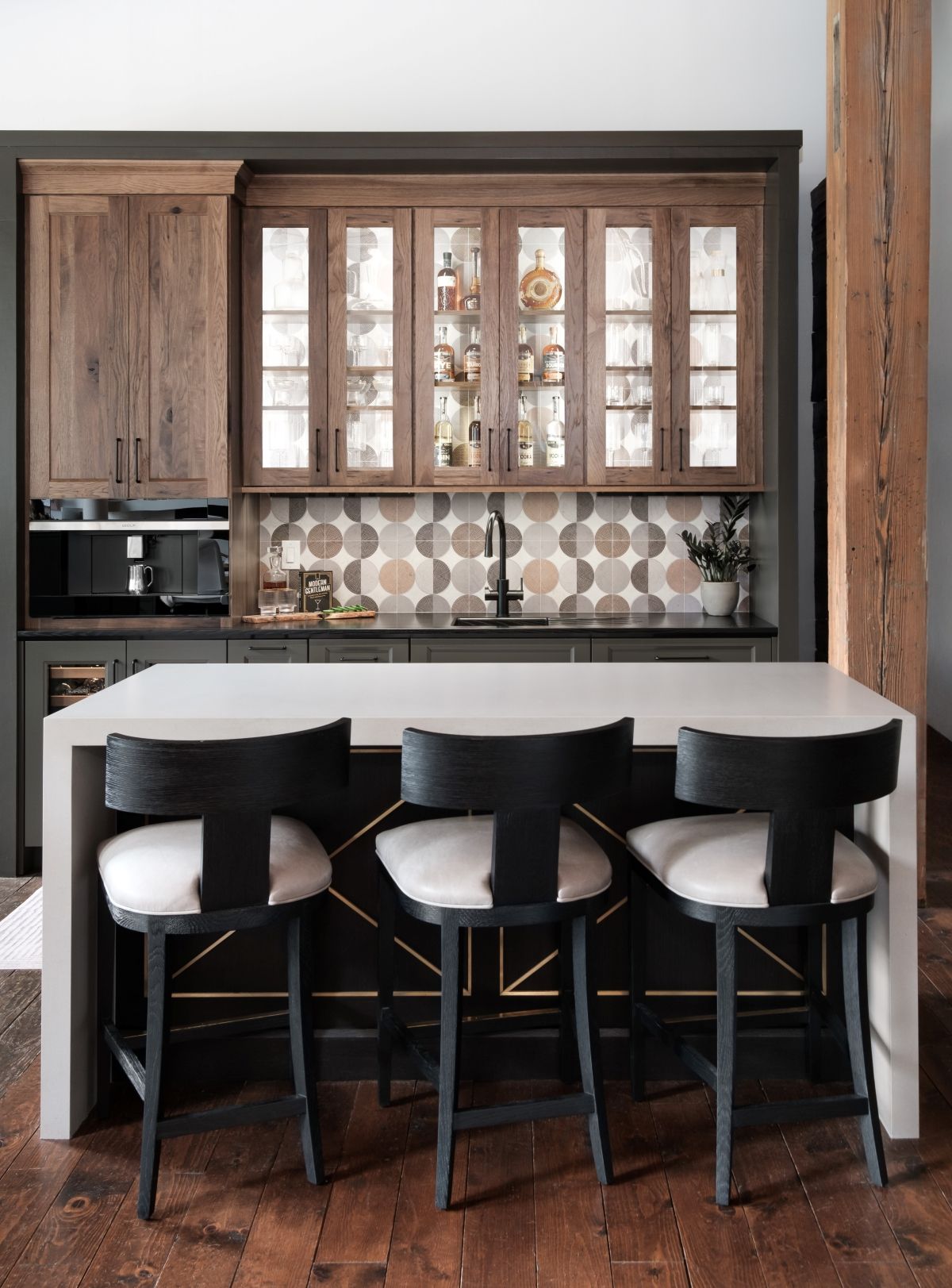 Modern kitchen with wood cabinets, patterned backsplash, island, and three black stools