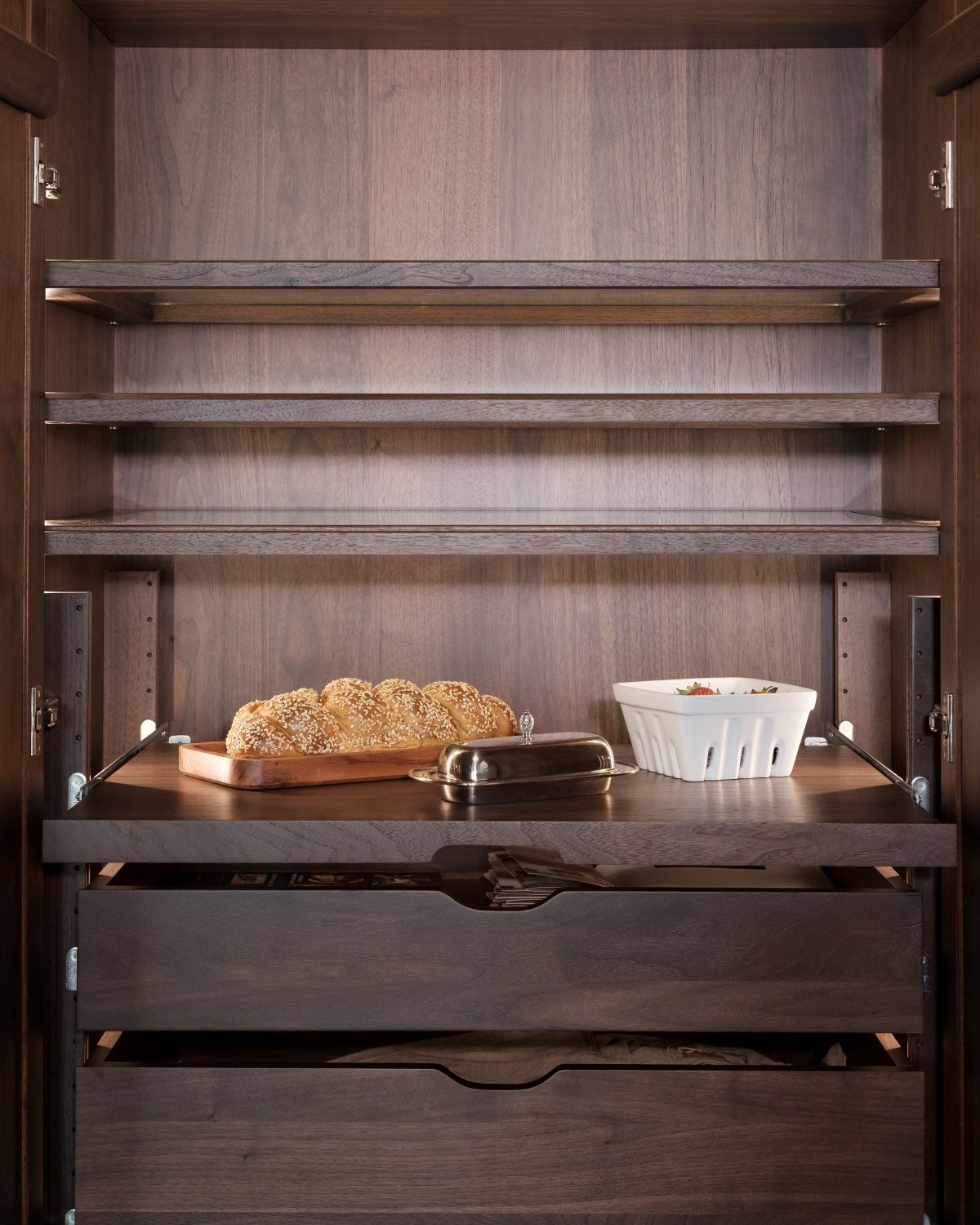 Empty wooden cabinet shelves with a loaf of bread and a small white cup on the middle shelf