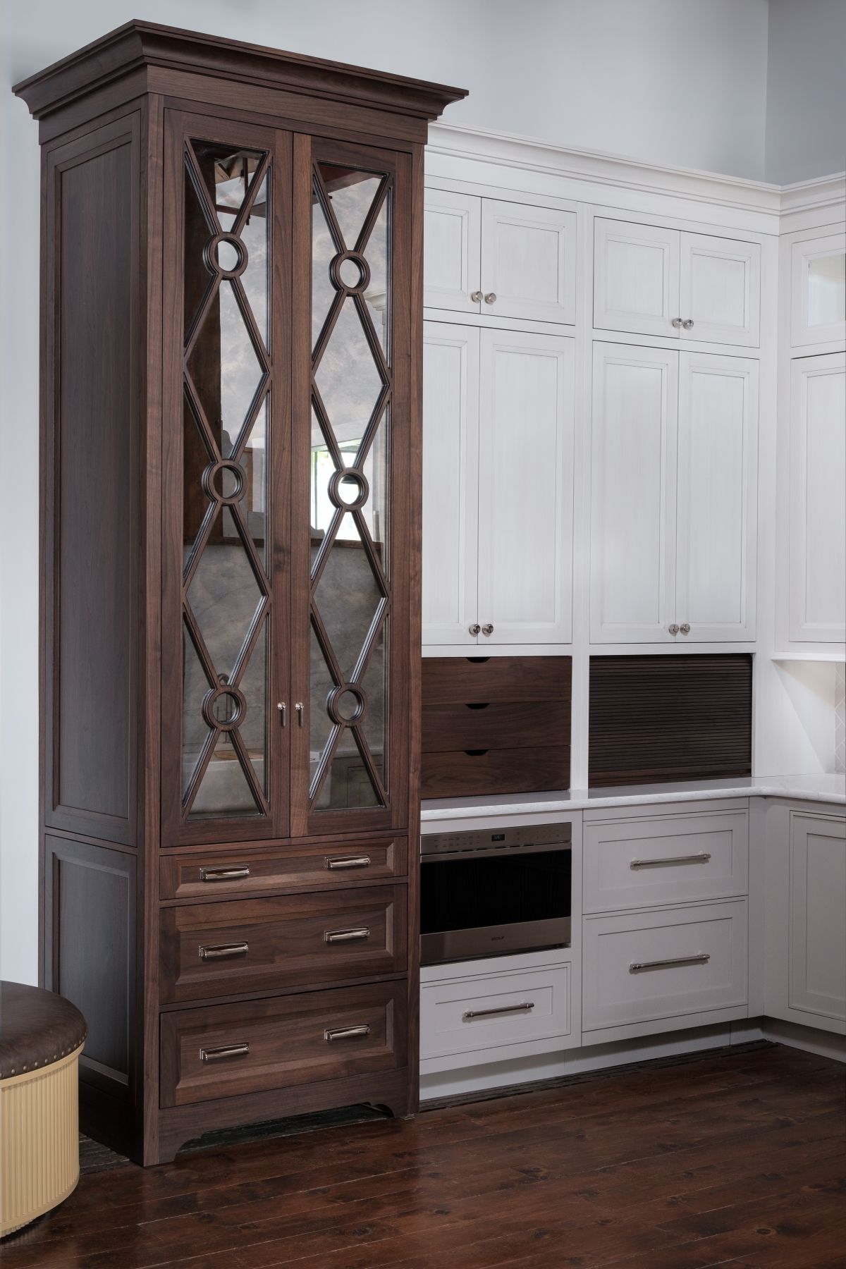Tall dark wood glass cabinet beside white built-in storage cabinets in a room