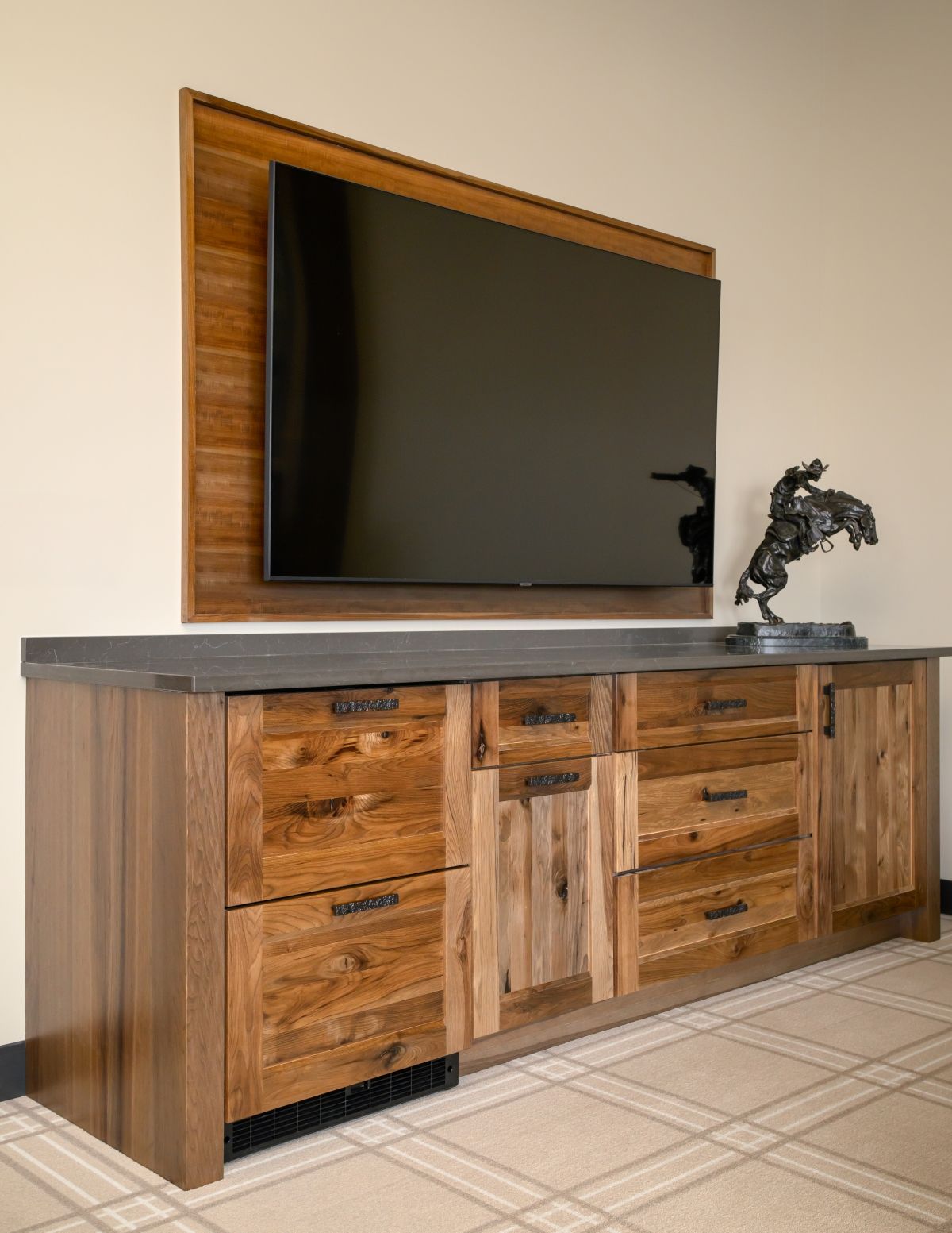 Modern wooden TV console with a large flat-screen and small horse sculpture in a living room.