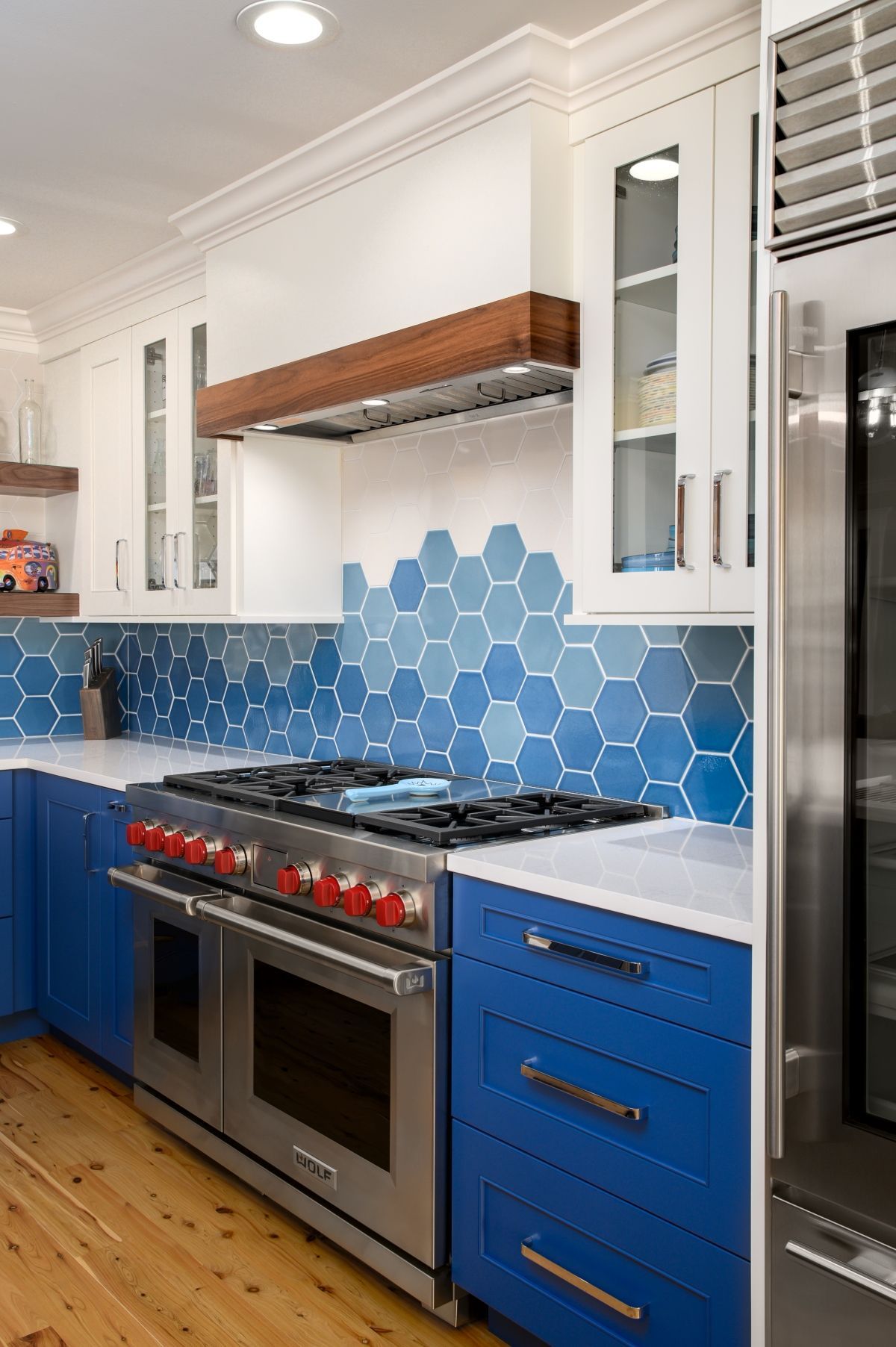 Modern kitchen with blue cabinets, hexagon tile backsplash, and stainless steel stove and fridge