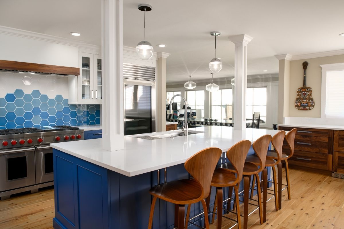 Modern kitchen with blue hex tile backsplash, white island, and wooden bar stools