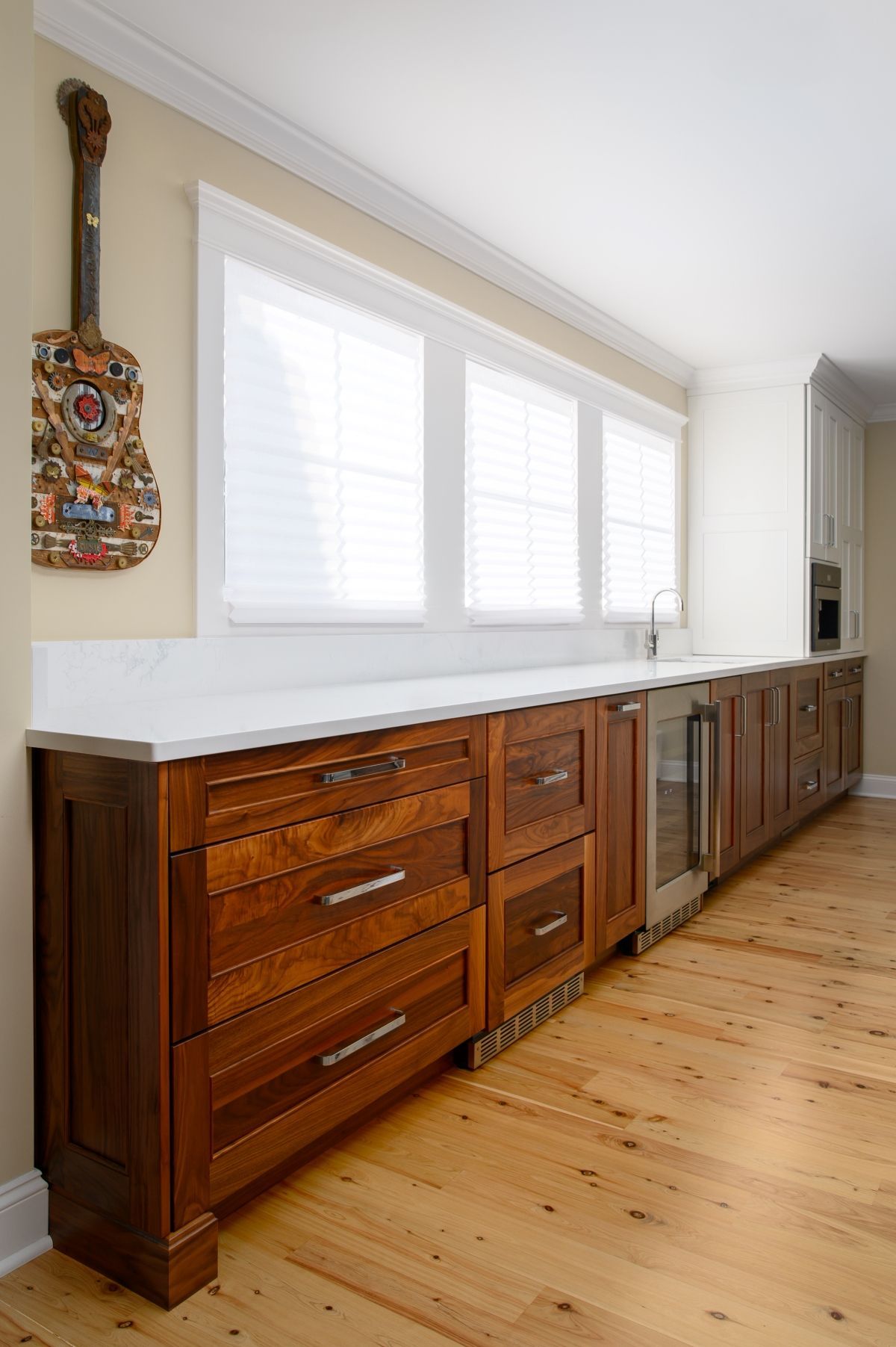 Long wooden sideboard beneath a bright window in a light wood-floored room