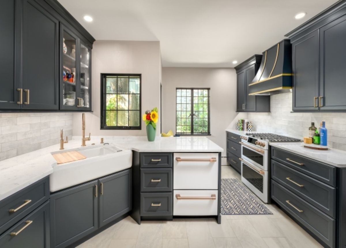 Modern kitchen with dark cabinets, white countertops, farmhouse sink, stove, and two windows