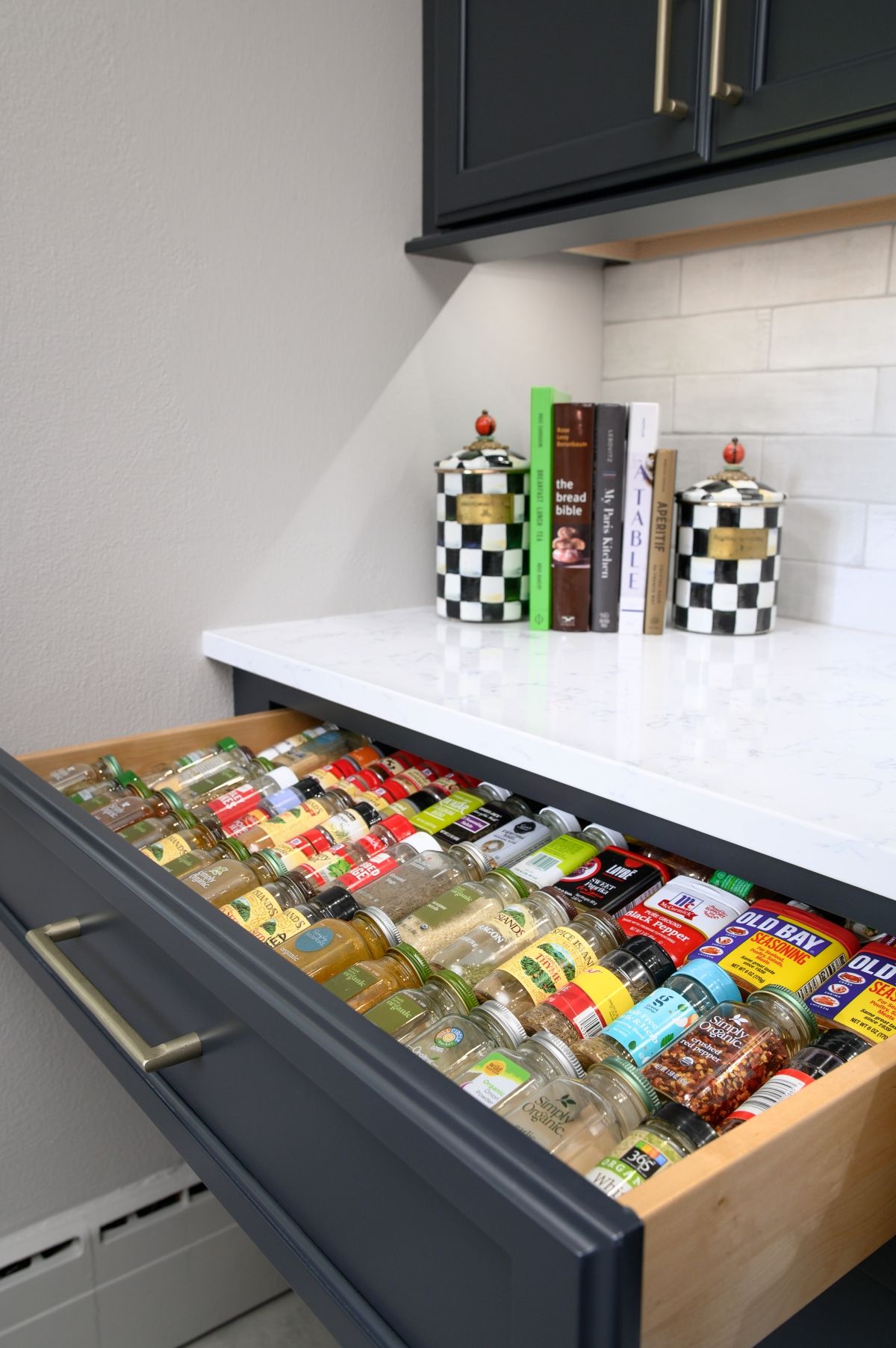 Open kitchen drawer filled with neatly arranged candy bars and snacks beneath a countertop.