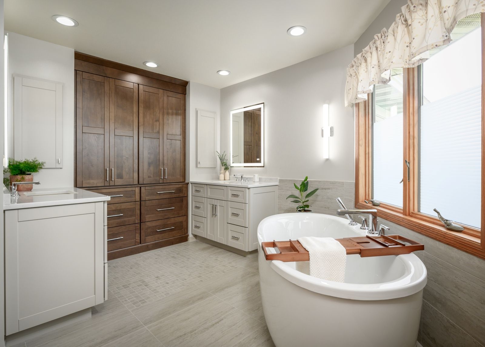 Bright modern bathroom with white vanity, dark wood cabinets, large window, and freestanding tub