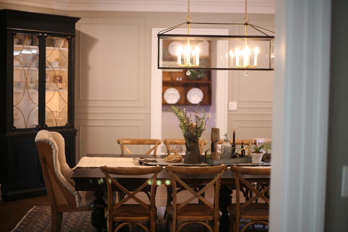 Elegant dining room with wooden table, upholstered chairs, chandelier, and built-in shelves with dishes.