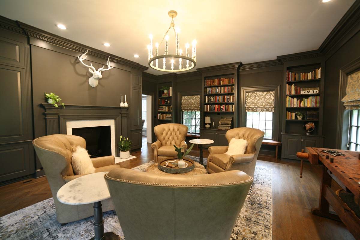 Elegant living room with fireplace, bookshelves, armchairs, and a central seating area under a chandelier