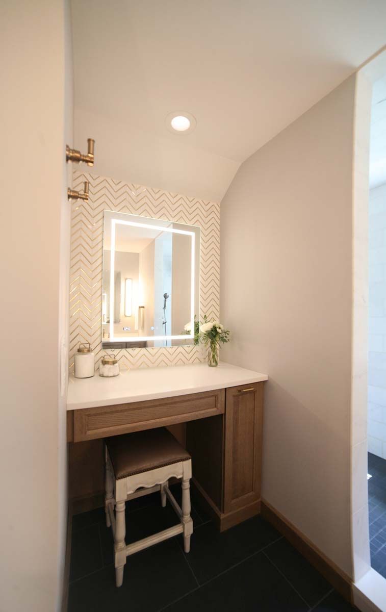 Small bathroom vanity with mirror, light wood cabinet, and black floor tiles in a narrow alcove.