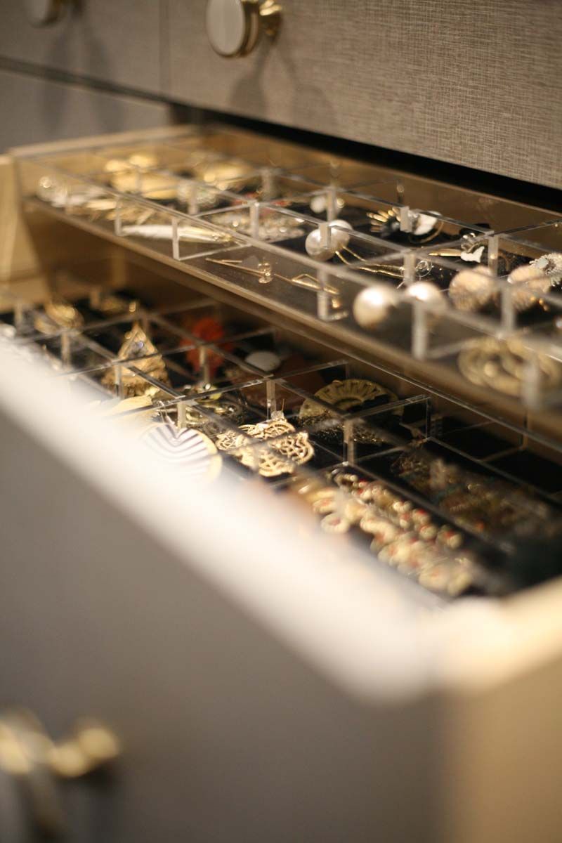 Jewelry displayed in a glass case with rows of rings and watches under warm lighting