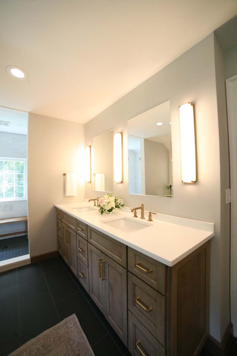 Modern bathroom vanity with double sinks, large mirror, and warm wall lights