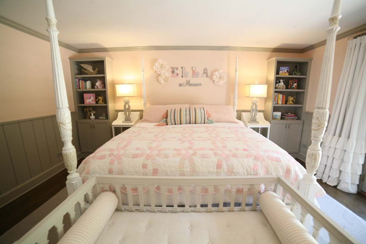 Pink-and-white bedroom with a four-poster bed, lamps, and matching bookshelves