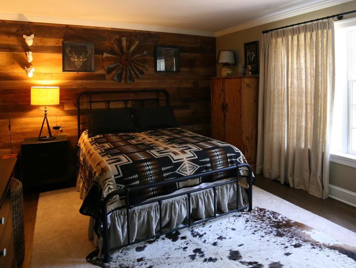 Cozy bedroom with a bed, lamp, wooden wall, closet, and sunlight through sheer curtains