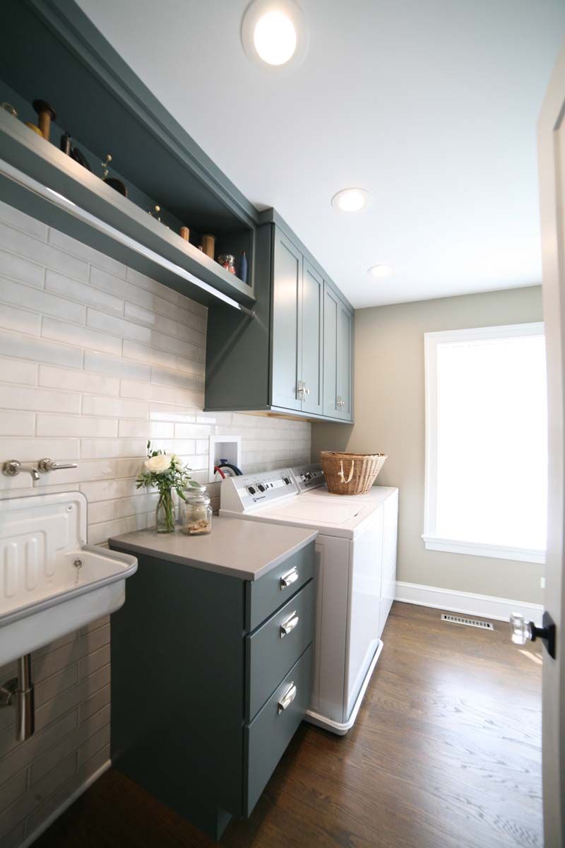 Narrow laundry room with dark cabinets, white washer, sink, and bright window lighting