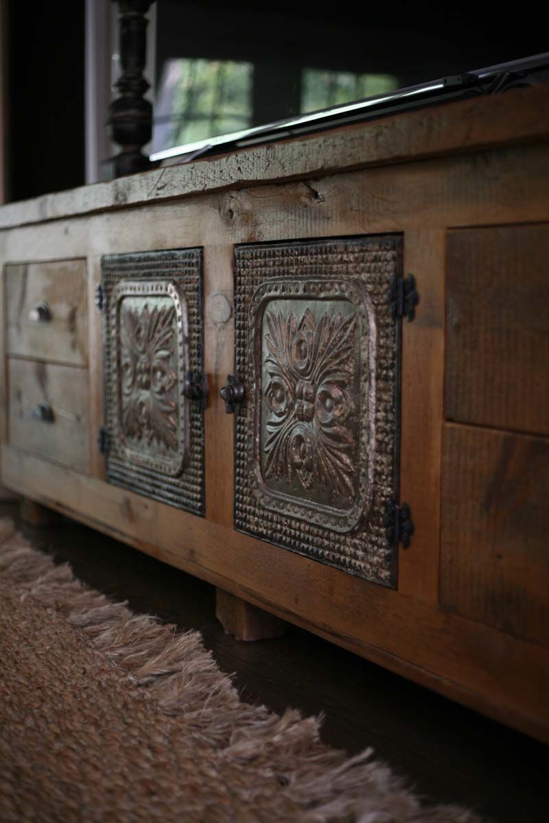 Wooden cabinet with two decorative metal panels on the front, viewed close up indoors
