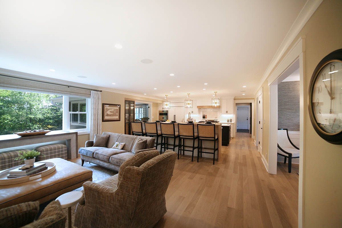 Spacious open-plan living room with gray sectional, dining table, and bright kitchen island behind