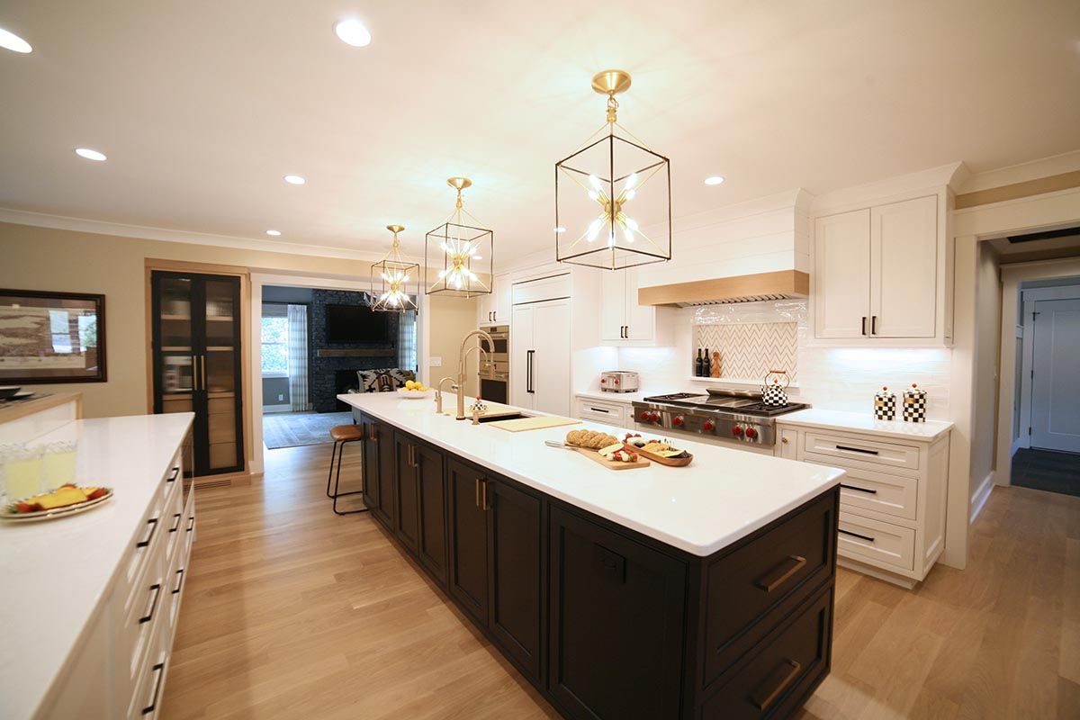 Bright modern kitchen with large island, white cabinets, and brass pendant lights