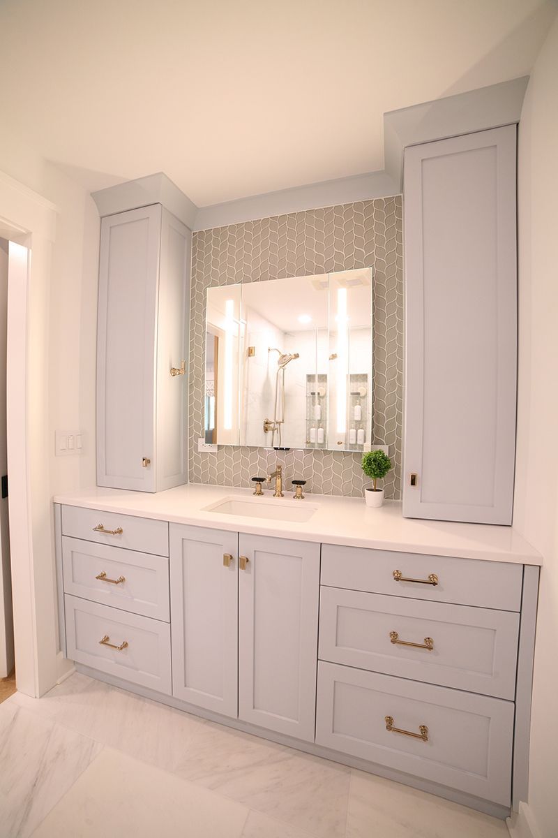 White bathroom vanity with double mirrors, drawers, and cabinets in a bright, tiled room
